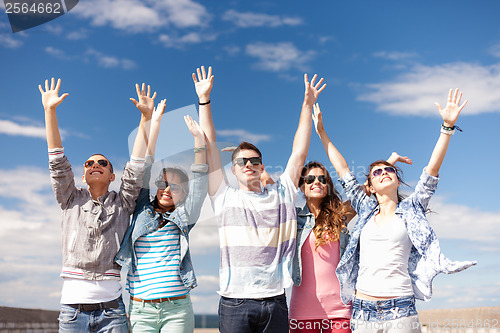 Image of group of smiling teenagers holding hands up