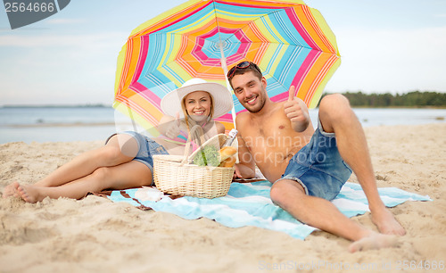 Image of smiling couple sunbathing on the beach