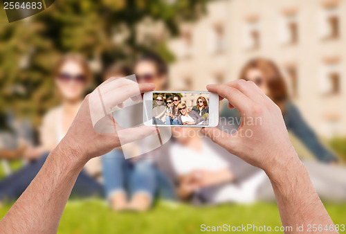 Image of close up of hands making picture of group of teens