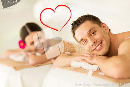 Image of smiling couple lying on massage table in spa salon