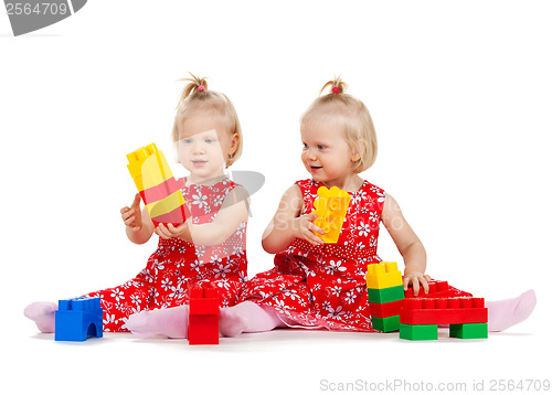 Image of two twin girls in red dresses playing with blocks