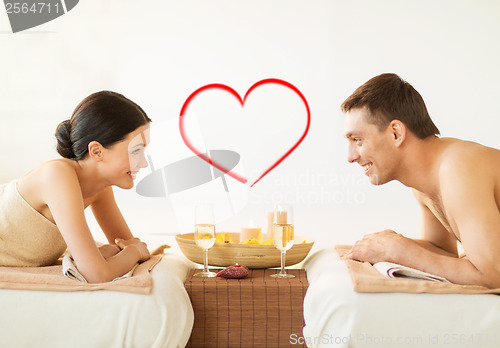 Image of smiling couple with candles and drinks in spa