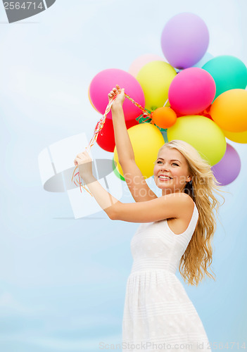 Image of smiling woman with colorful balloons outside