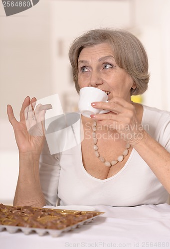 Image of Senior woman eats chocolate candies