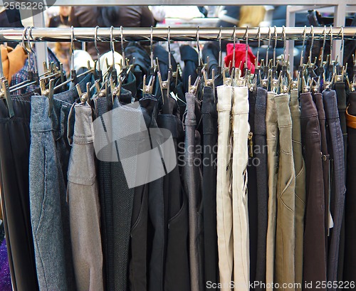 Image of group different colored jeans hanging on a hanger in store