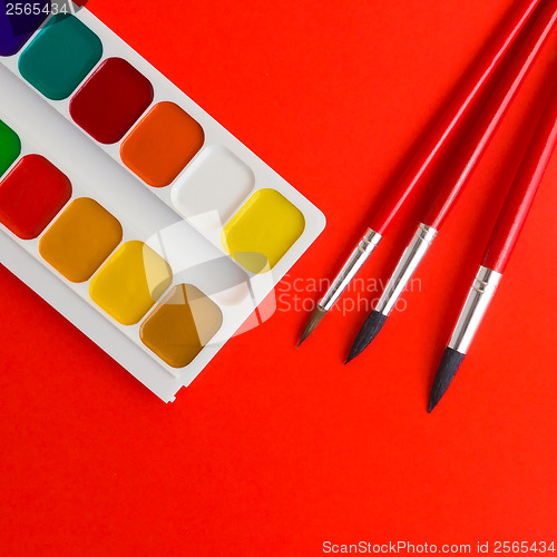 Image of paints and brushes on the red texture art palette