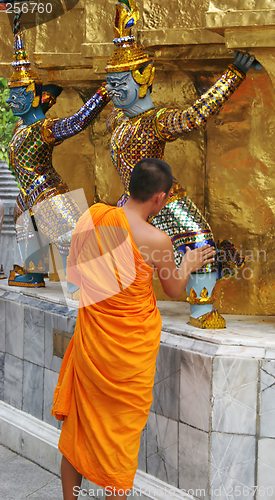 Image of Monk inspects a statue at the Grand Palace, Bangkok, Thailand -