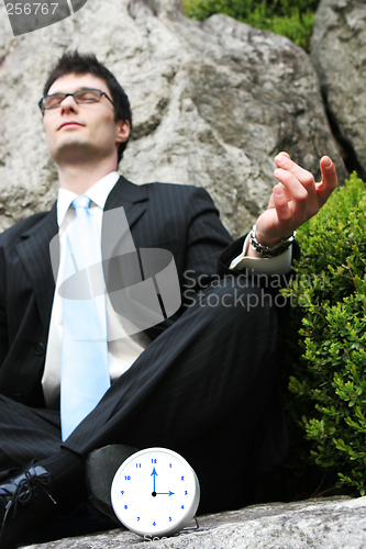 Image of Businessman meditating outside.