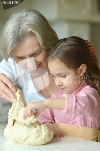 Image of Little girl kneading dough with grandmother