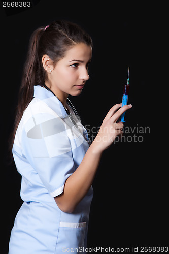 Image of Young female doctor with stethoscope and syringe