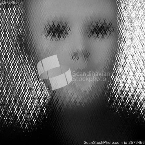 Image of masked figure behind glass