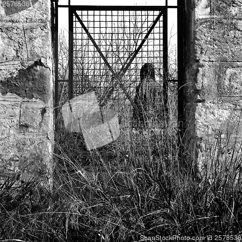 Image of man behind vintage metal door and overgrown plants