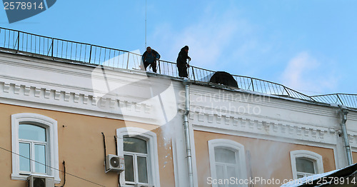 Image of Workers clean snow from the roof