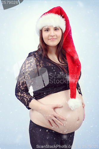 Image of beautiful pregnant santa woman tenderly holding her tummy