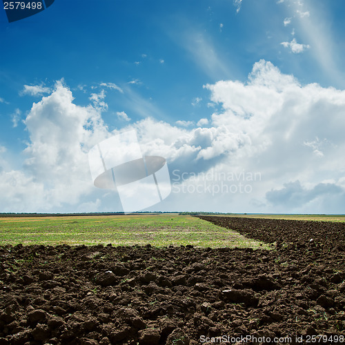 Image of green and plowed fields under cloudy sky