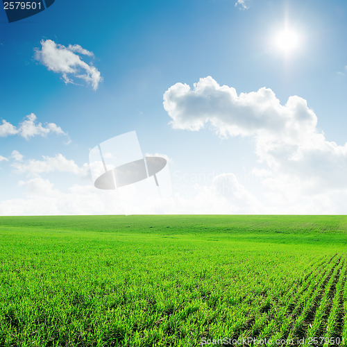 Image of sun in blue sky with clouds and green field