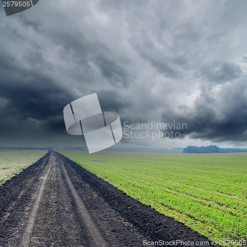 Image of road in green fields to low rainy clouds