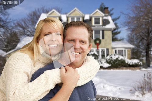 Image of Couple in Front of Beautiful House with Snow on Ground