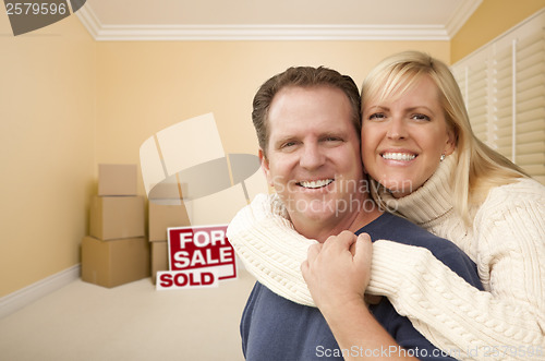 Image of Couple in New House with Boxes and Sold Sale Sign