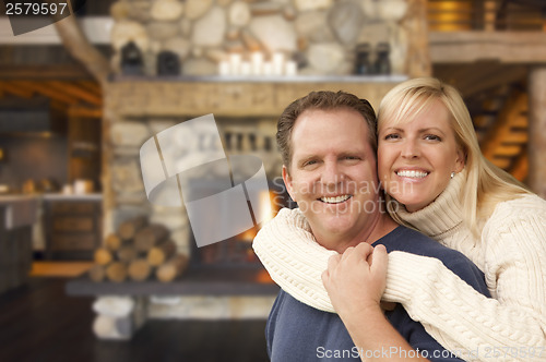 Image of Affectionate Couple at Rustic Fireplace in Log Cabin