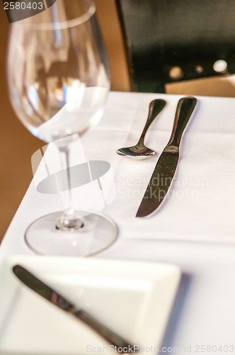 Image of elegant dinner table set with knife fork and wine glass