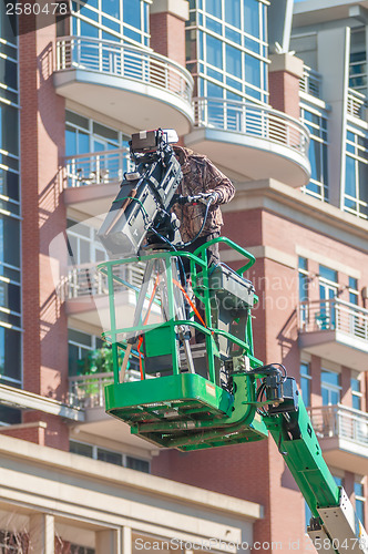 Image of tv camera man recording event in a city on a lift