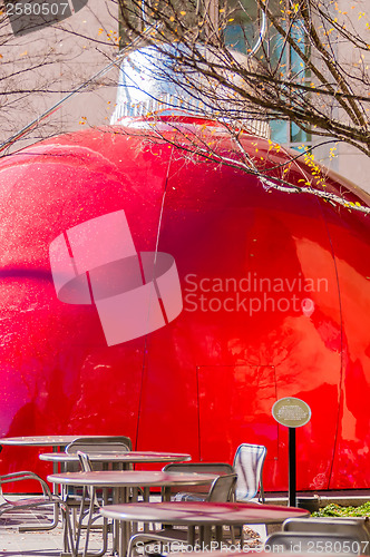 Image of giant red bauble on city plaza behind eating table area