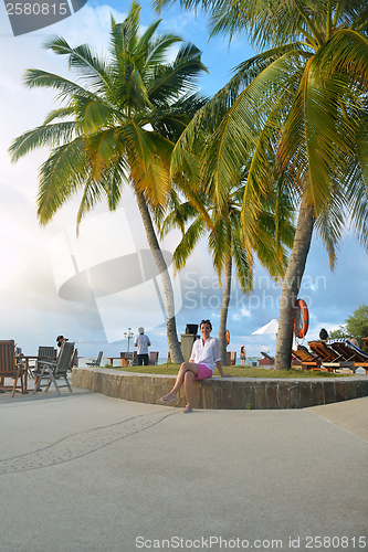 Image of Beautiful young woman with a drink by the sea