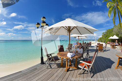 Image of Beautiful young woman with a drink by the sea