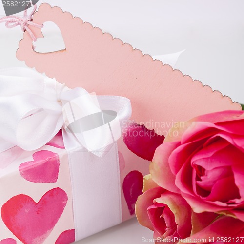 Image of Gift box with an empty tag, next to three roses