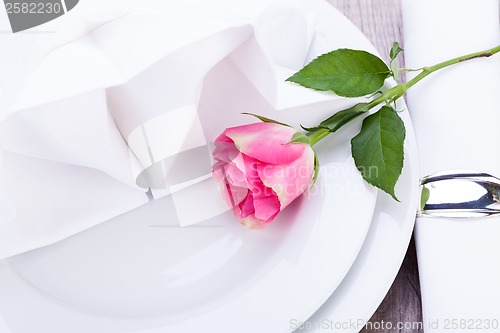 Image of Table setting with a single pink rose