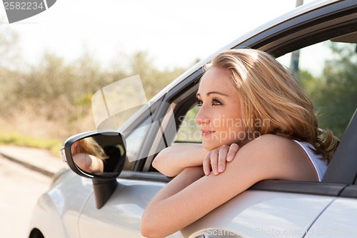 Image of young attractive happy woman sitting in car summertime
