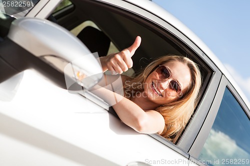 Image of young attractive happy woman sitting in car summertime