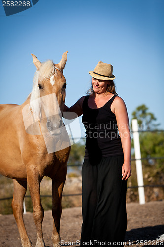 Image of young woman training horse outside in summer