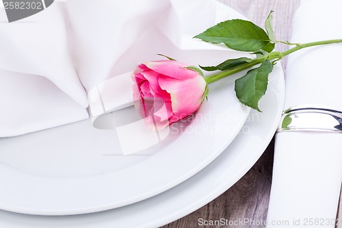 Image of Table setting with a single pink rose