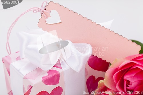 Image of Gift box with an empty tag, next to three roses