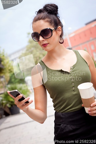 Image of attractive young woman with smartphone and sunglasses outdoor