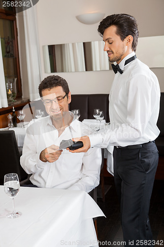 Image of dinner in restaurant man and woman pay by credit card