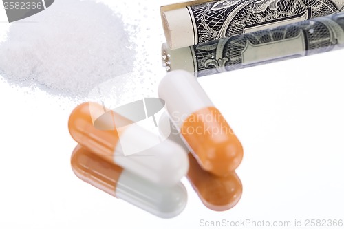 Image of illegal pharmaceutical pills and drugs money on mirror