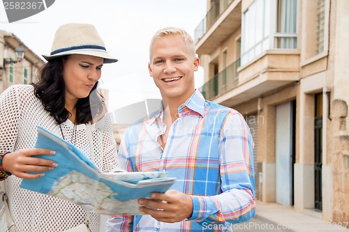 Image of Young couple of tourists consulting a map