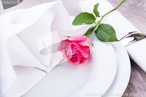 Image of Table setting with a single pink rose