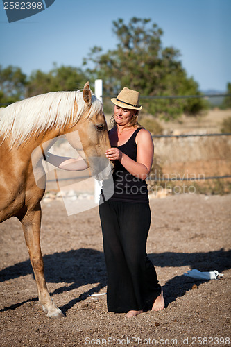 Image of young woman training horse outside in summer