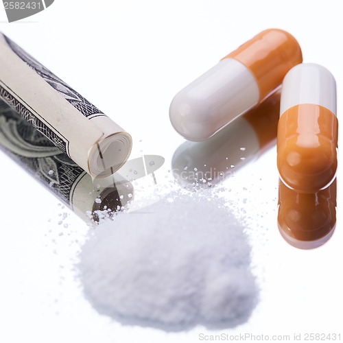 Image of illegal pharmaceutical pills and drugs money on mirror