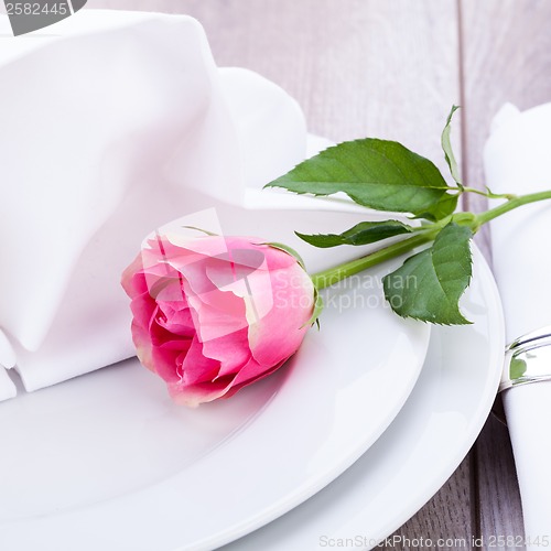 Image of Table setting with a single pink rose