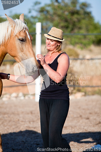 Image of young woman training horse outside in summer