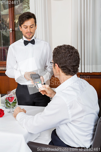 Image of dinner in restaurant man and woman pay by credit card