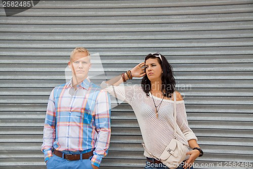 Image of Fashionable couple posing in front of a metal door