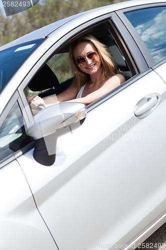 Image of young attractive happy woman sitting in car summertime