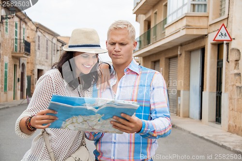 Image of Young couple of tourists consulting a map