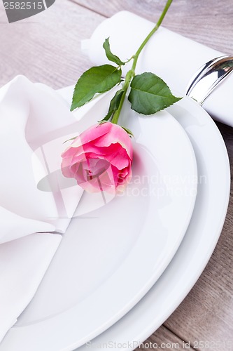 Image of Table setting with a single pink rose